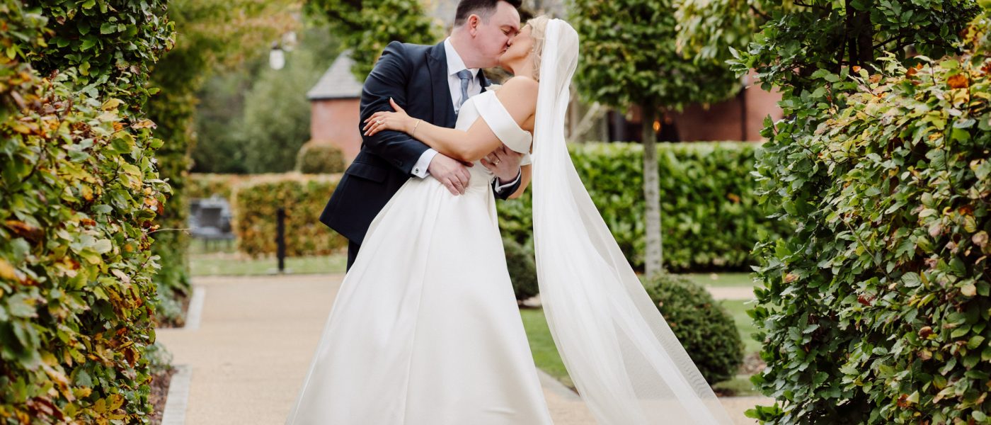 Bride and groom embracing and kissing in a lush garden setting, showcasing a romantic moment for wedding photography in Northern Ireland.